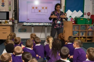 A teacher teaching in front of a classroom of kids.