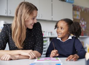 Female teacher supports female pupil with learning