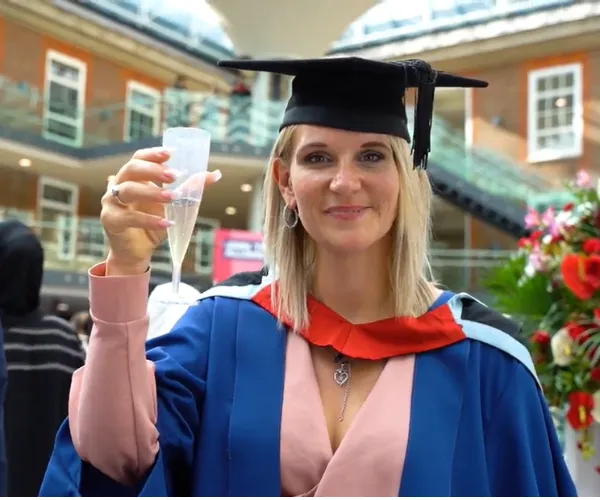 A graduand holding a celebratory glass of champagne