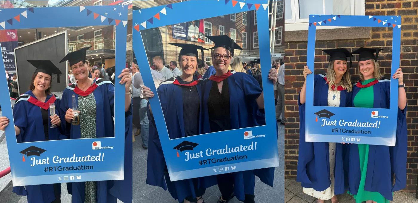 an image of graduates holding a blue selfie frame and smiling at the camera on their graduation day